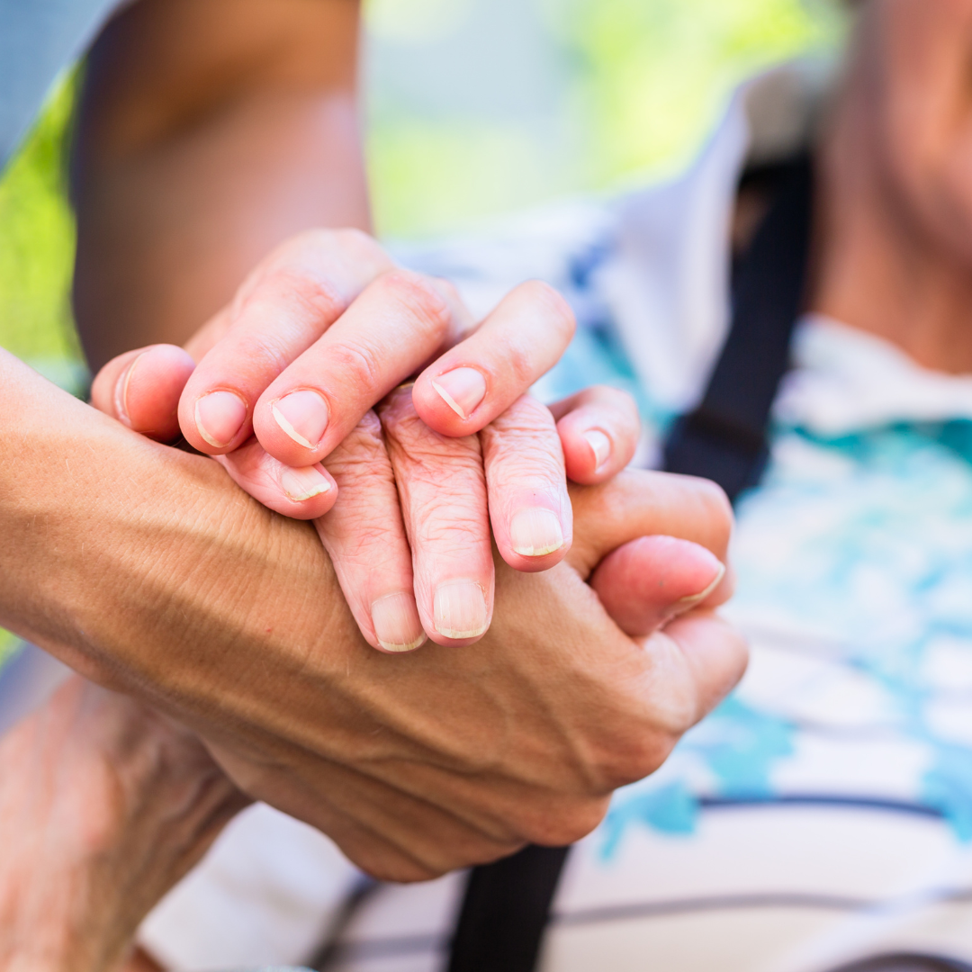 A caring individual holding an elderly person's hand.